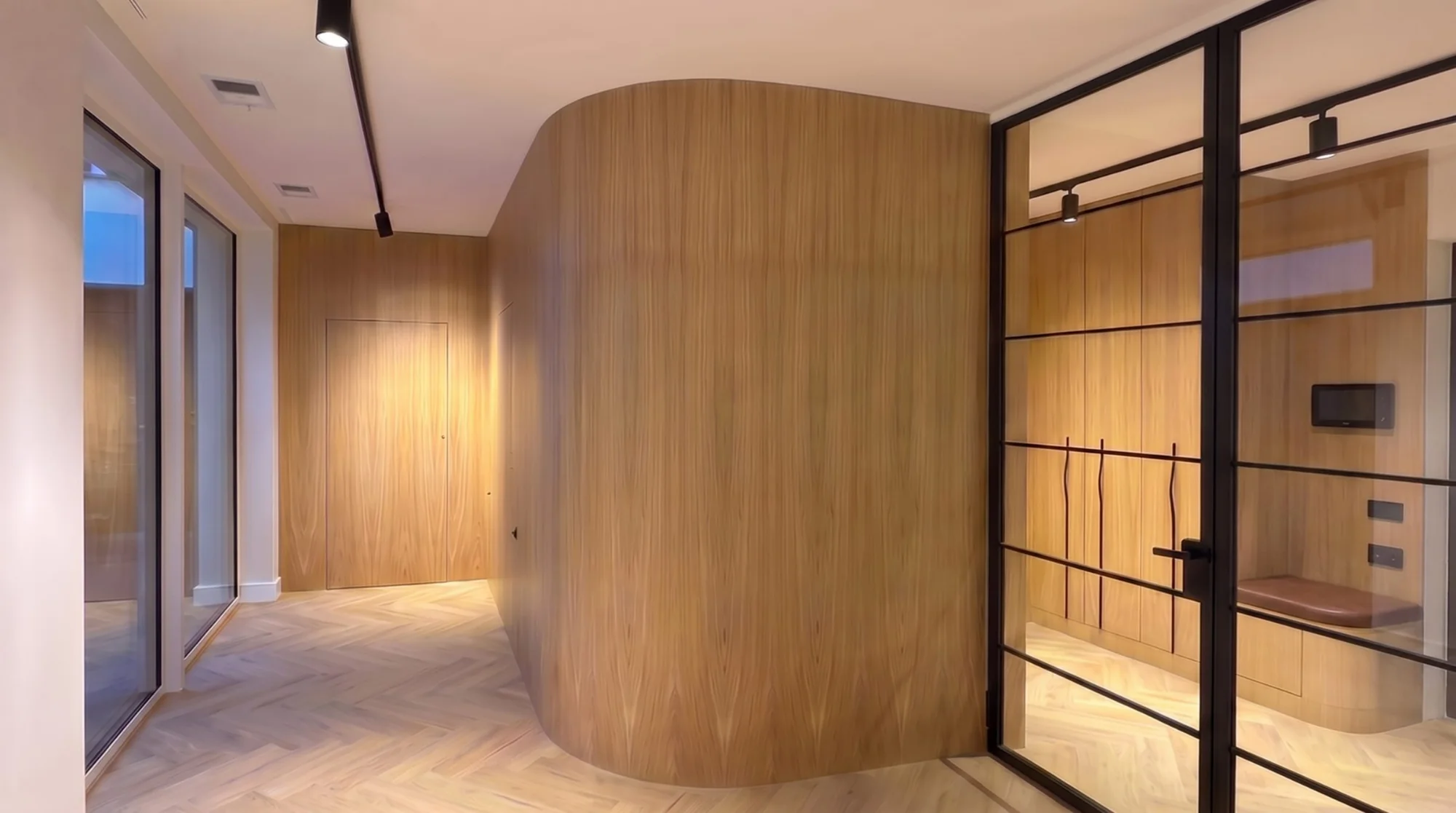 Curved integrated veneered wall system in a hallway, concealed doors with no handles visible from without — a Creadoor project